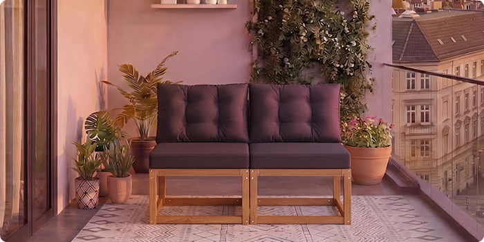 Dvosjedna modularna drvena sofa s tamnosi vim jastucima na balkonu okruženom loncima s biljkama i pogledom na grad u pozadini