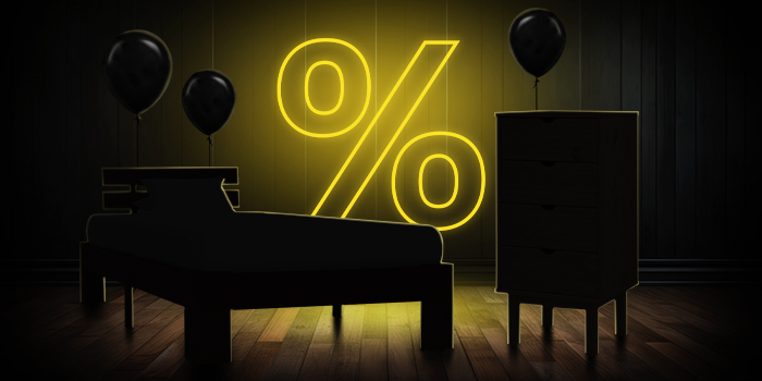  Crni krevet i komoda s crnim balonima ispred svijetlo žutog znaka postotka na tamnom drvenom podu.